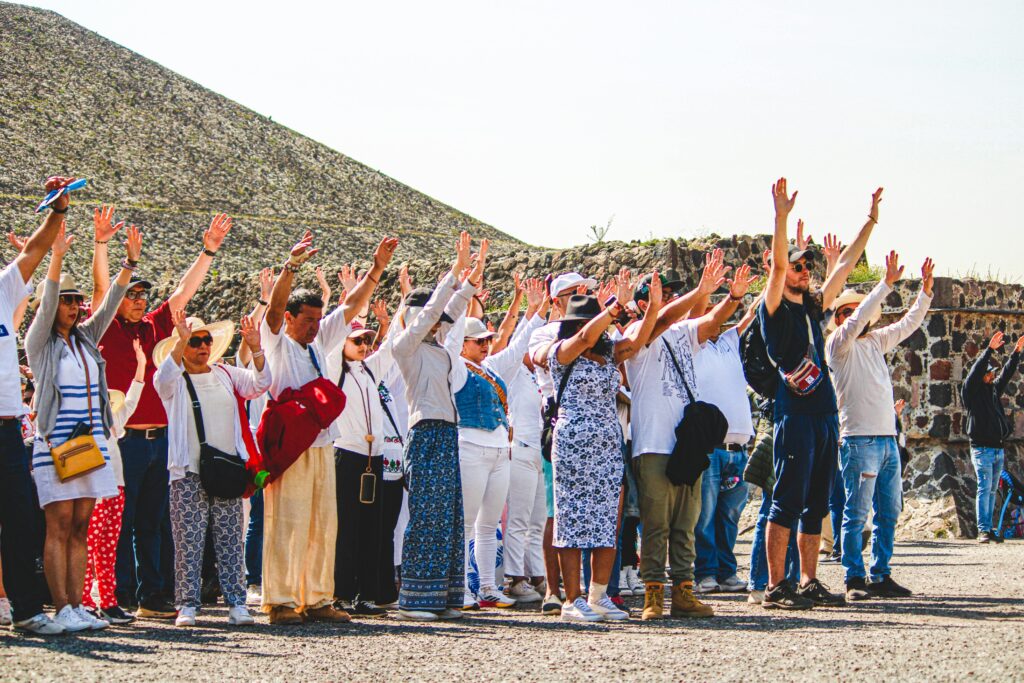 Group of travelers celebrating together in an outdoor tour setting with mountains and stadium in background
